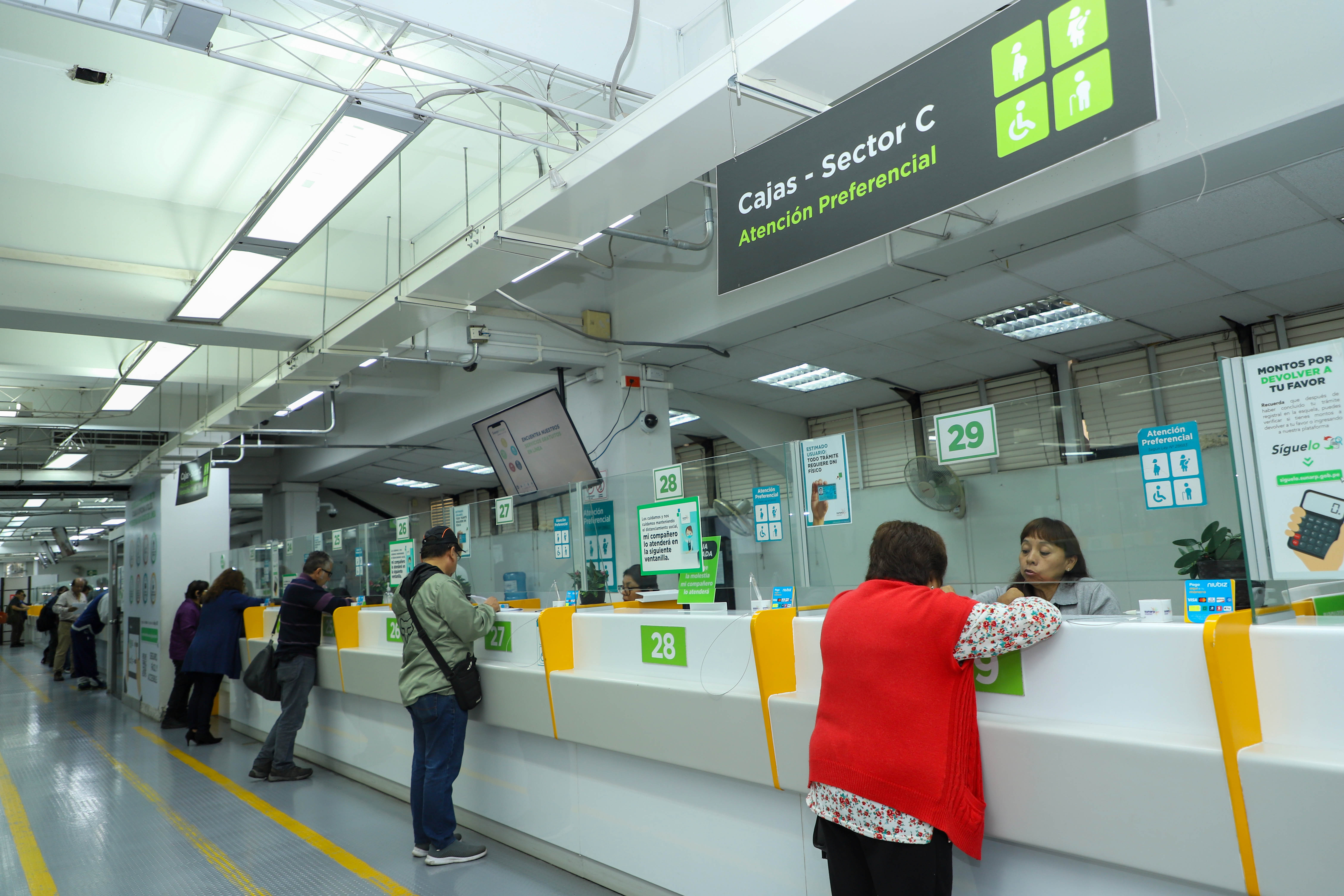 Foto de Varias personas siendo atendidas en ventanillas por personal de la Sunarp