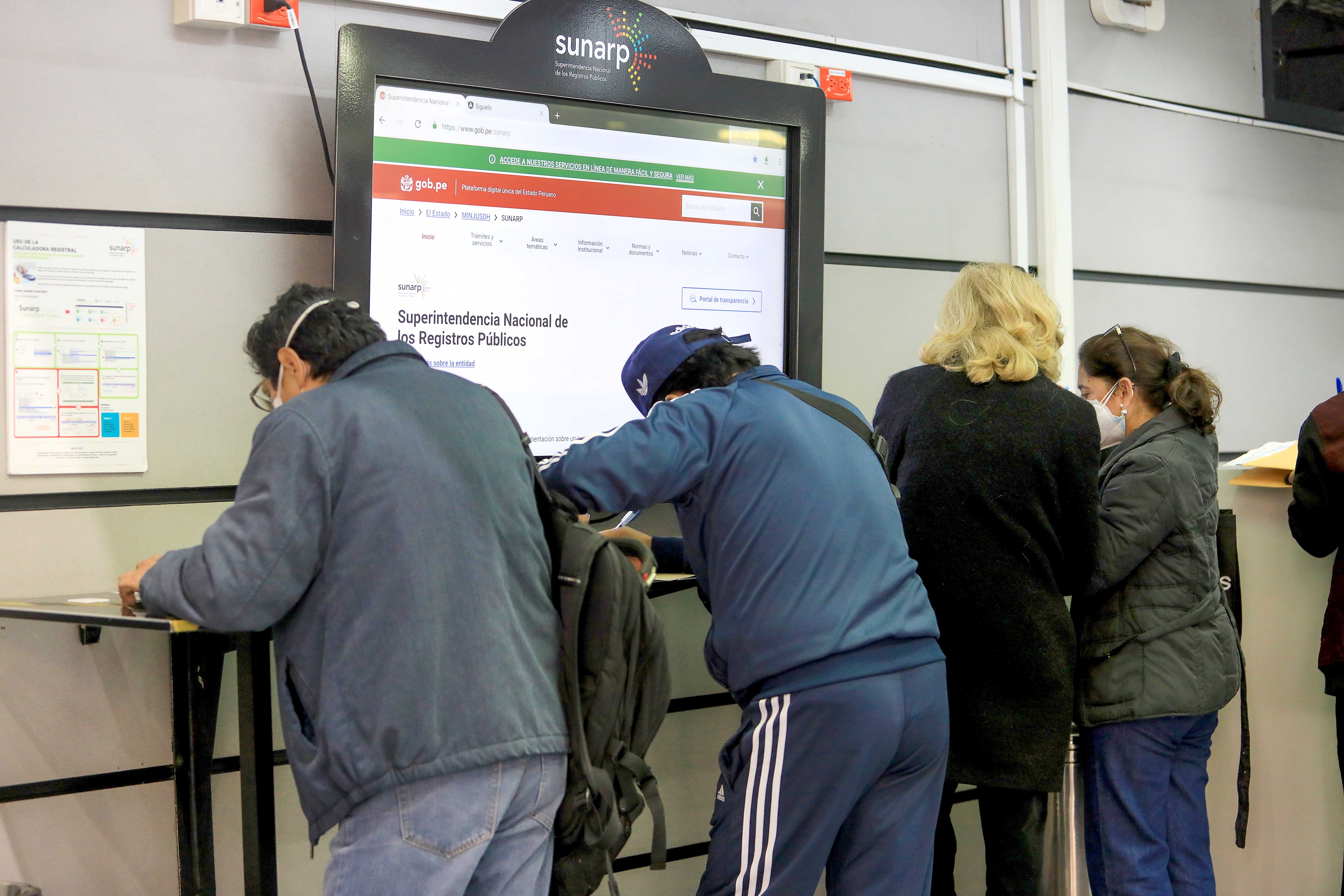 Foto de Personas llenando sus formularios para hacer trámites en oficina de la Sunarp