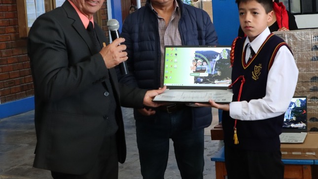 Directivos entregando laptop a estudiante de primaria