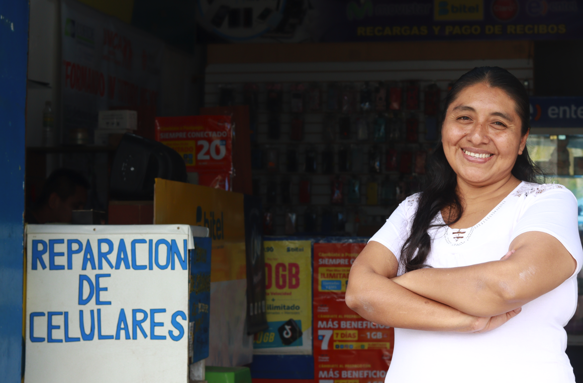 Imagen de mujer emprendedora en la puerta de su negocio de reparación de celulares