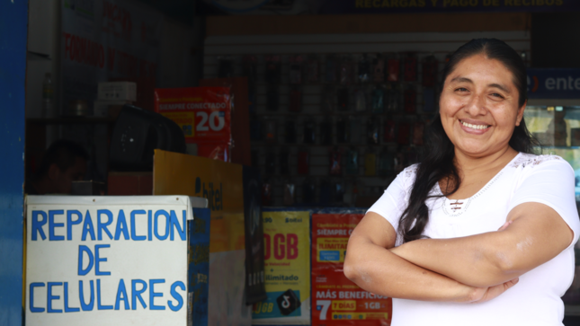 Imagen de mujer emprendedora en la puerta de su negocio de reparación de celulares