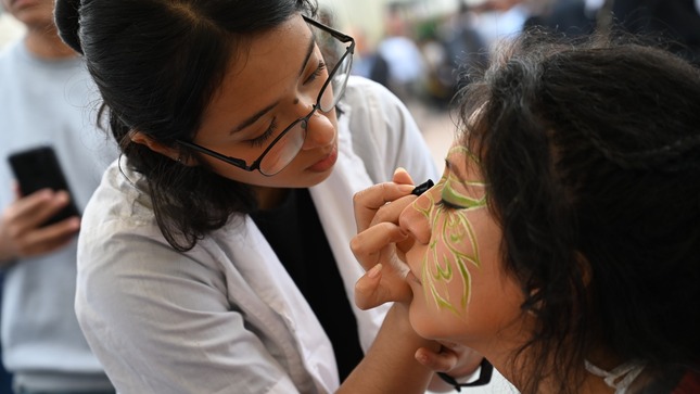 En feria tecnológica, joven hace una muestra de lo que aprenderán en la carrera de cosmetología.
