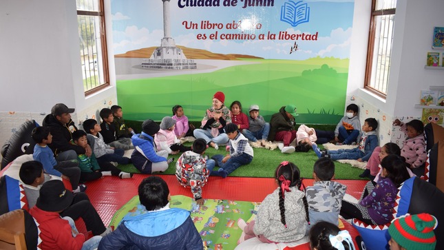 La escritora Rosalba Salazar Gallo cautiva a un grupo de niños en la celebración del Día Internacional de las Bibliotecas en Junín. Sus expresiones reflejan la conexión mágica entre la narradora y su joven audiencia.