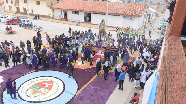 En la procesión, el sacerdote lidera con vestimenta morada, seguido de autoridades municipales, incluyendo a la primera regidora Karen Pucuhuaranga León, con trajes formales. Los fieles, vestidos también de morado, acompañan al Cristo, creando un ambiente devoto y comunitario.