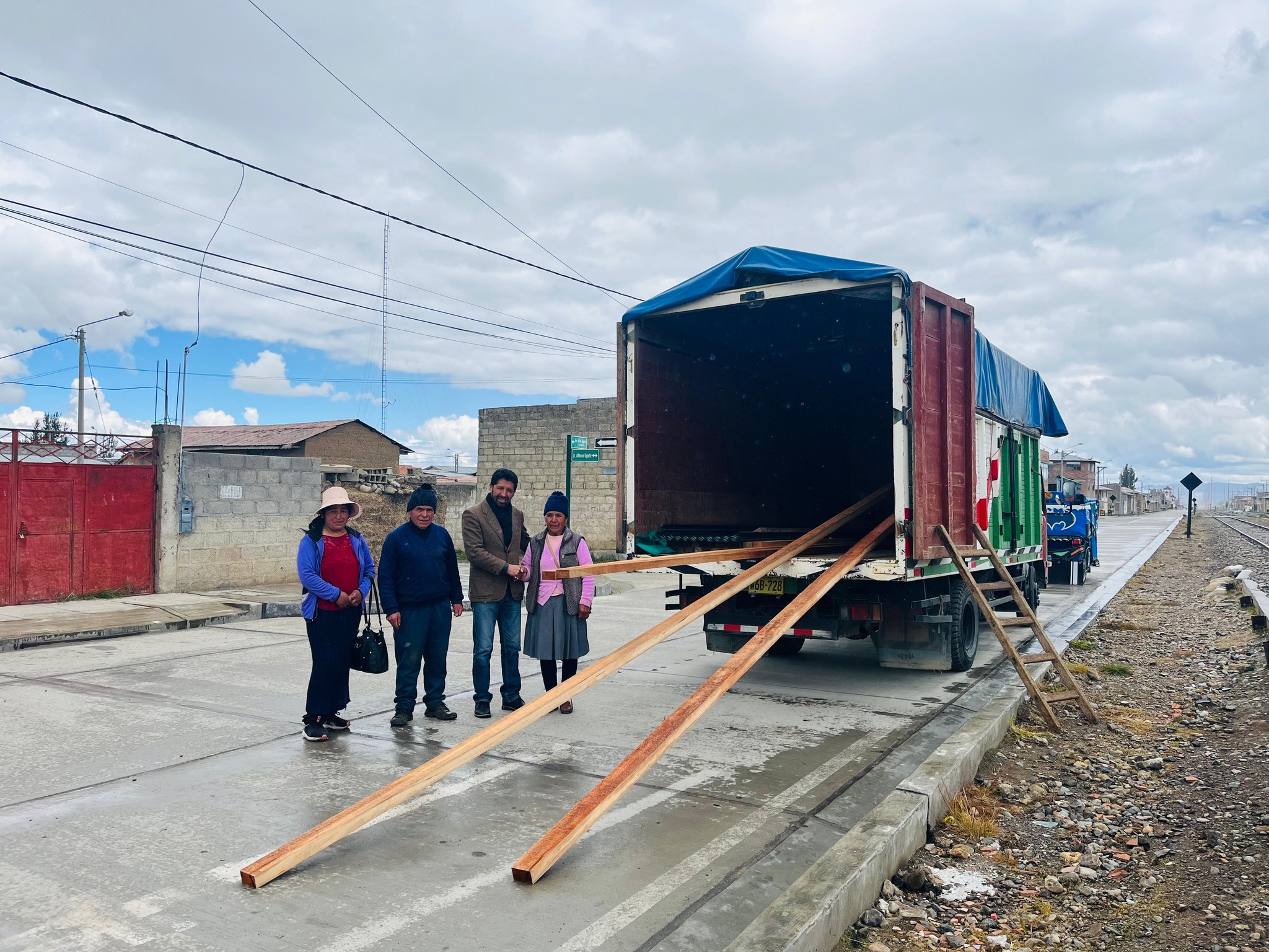 La imagen muestra al alcalde de Junín junto a tres personas, cerca de materiales de construcción entregados para el centro poblado de Rayannioc - Rucubamba. La escena refleja un compromiso visible hacia el desarrollo local, destacando la colaboración entre la municipalidad y la comunidad.
