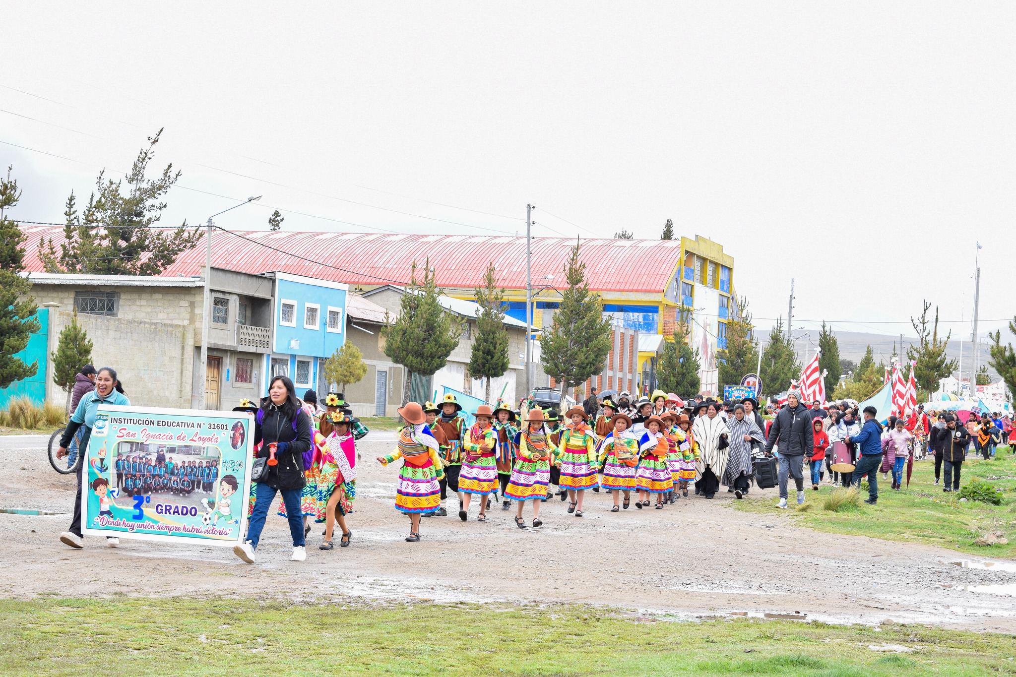 La imagen captura la energía y diversidad del pasacalle, con participantes vistiendo trajes tradicionales mientras realizan sus danzas. El colorido y la armonía visual reflejan la riqueza cultural del evento, creando una estampa festiva llena de alegría y dedicación. La imagen transmite la vitalidad y conexión con las tradiciones que define el pasacalle comunitario