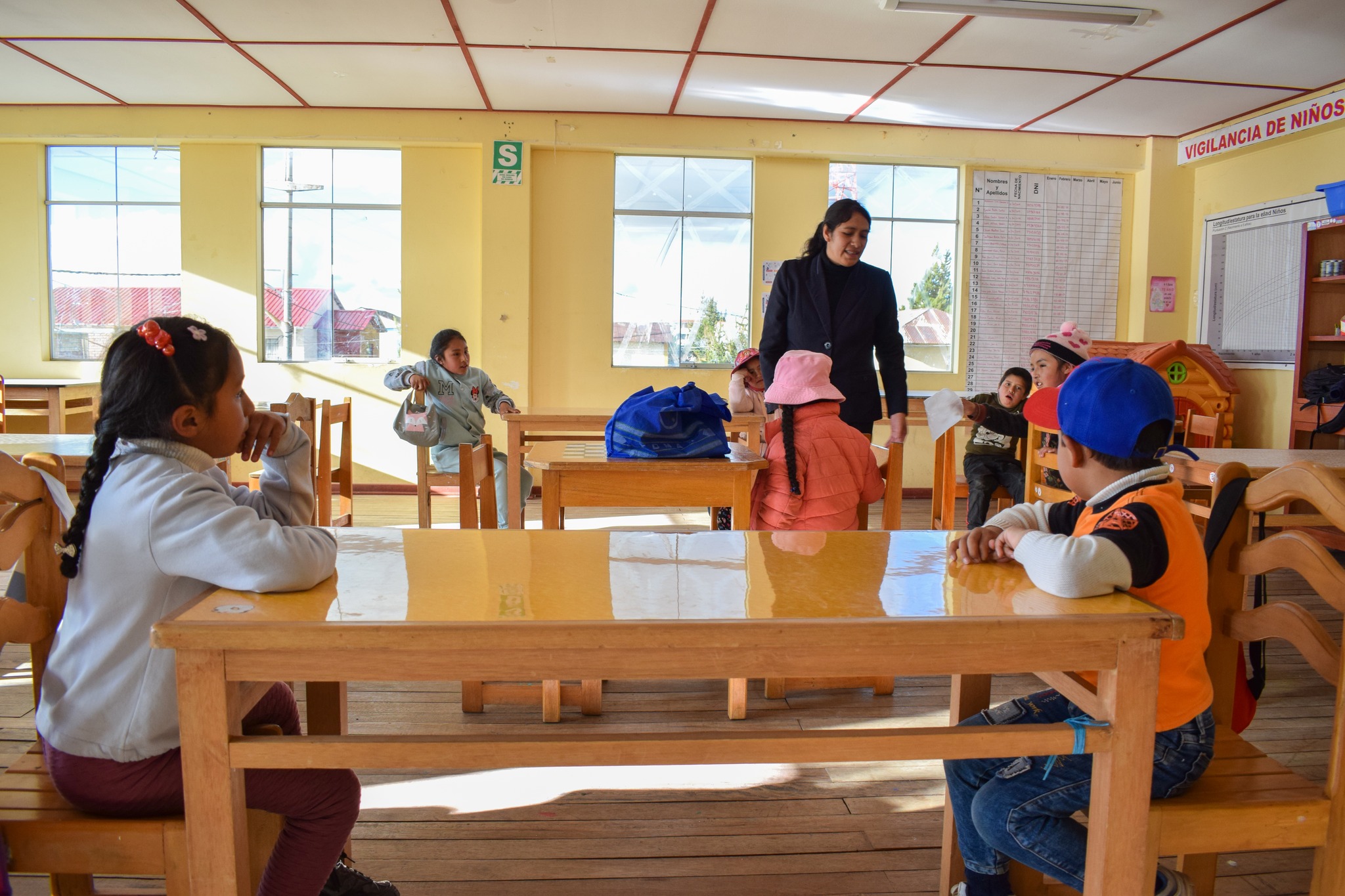 La imagen muestra a la profesora liderando el nuevo aula del taller "Junín, Bicentenario en la Huella de la Historia". Los niños, rodeados de colores y materiales artísticos, muestran entusiasmo mientras exploran su creatividad. La escena refleja el inicio emocionante de este viaje educativo y artístico