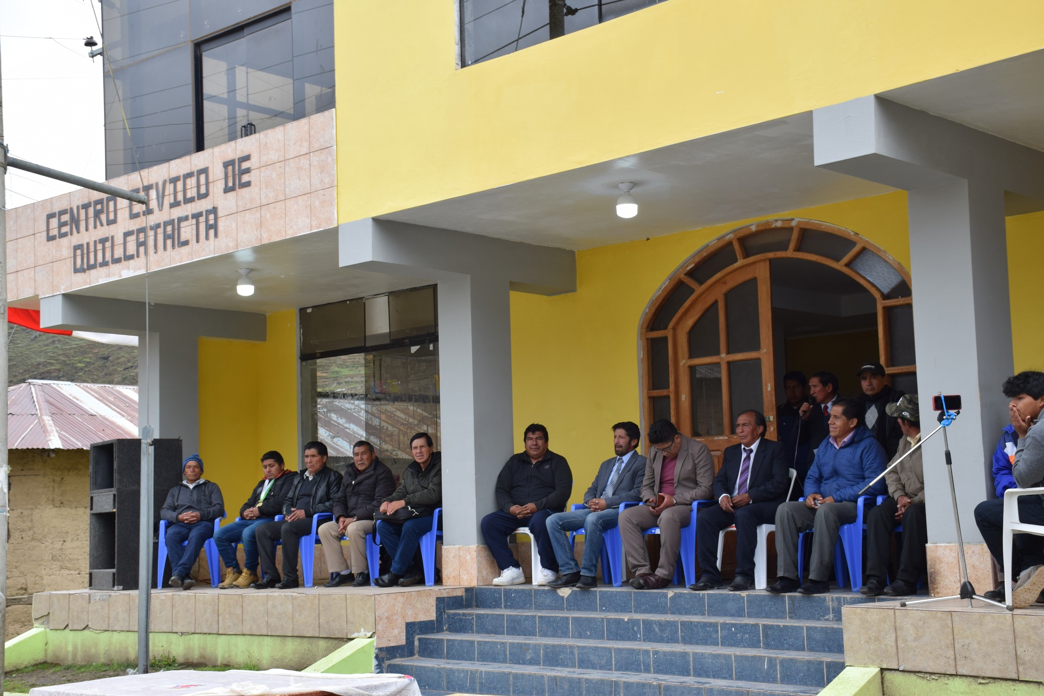 La imagen destaca al Alcalde de Junín, Elio Munzón Zevallos Meza, junto a representantes locales en la celebración del aniversario de Quilcatacta. Los gestos reflejan unidad y compromiso. Anuncios importantes para el desarrollo de la comunidad se comparten, creando un ambiente de solemnidad y esperanza.