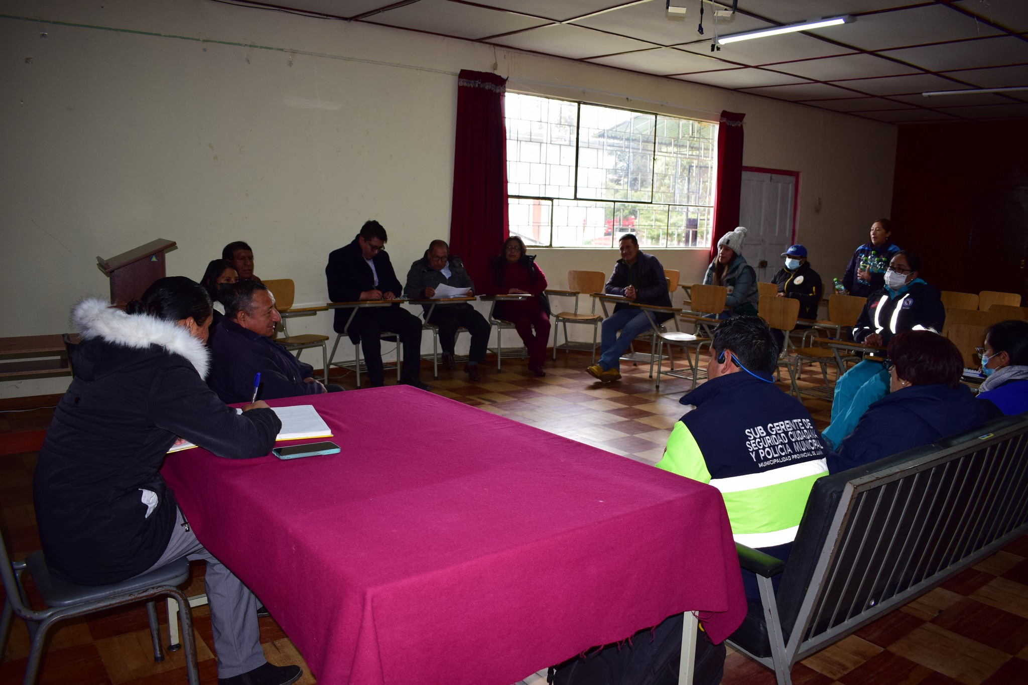 La imagen muestra a Condor Surichaqui liderando una reunión en el Centro de Salud Junín, con autoridades clave discutiendo estrategias para prevenir el fenómeno del Niño. El ambiente refleja cooperación y compromiso, capturando un momento crucial de planificación para garantizar la seguridad ante posibles eventualidades.