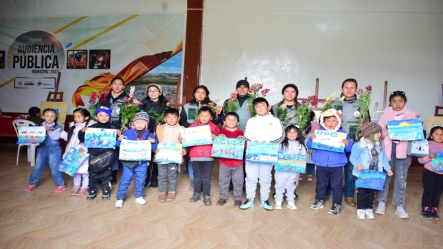 En la imagen podemos ver que los niños nos están mostrando sus pinturas realizadas y los encargados de medio ambiente están sosteniendo algunas flores que están listas para plantar. 