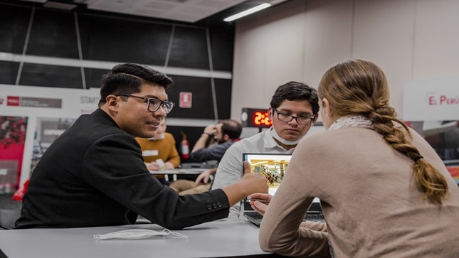 Tres personas conversando sobre una imagen en una laptop