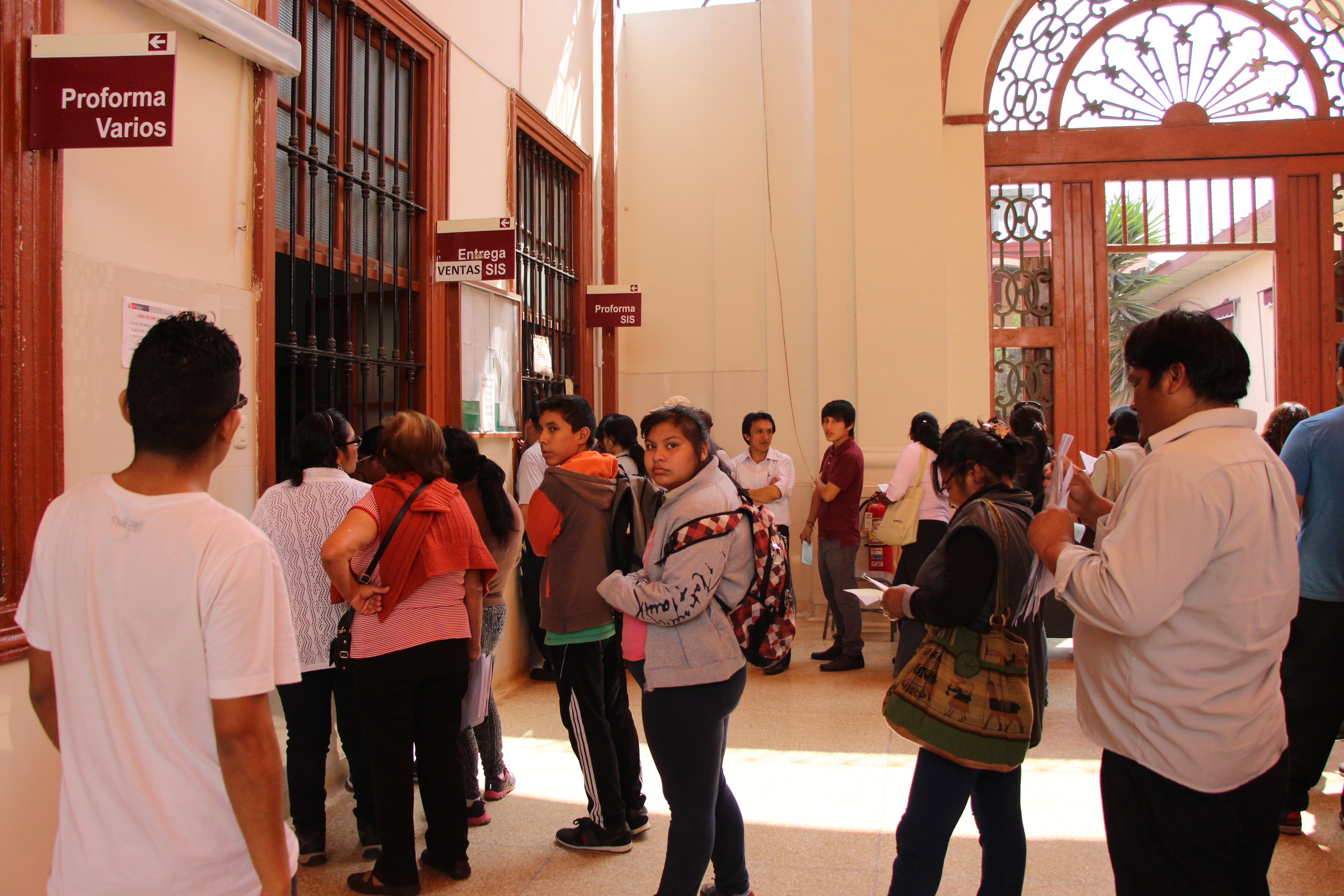 Personas haciendo cola para atención frente a ventanilla de farmacia