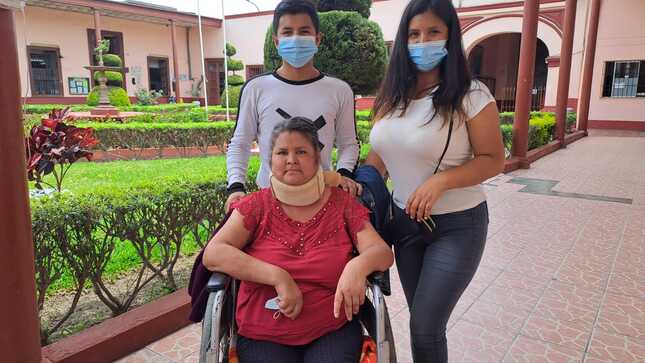 Paciente sentada en silla de ruedas rodeada de sus hijos