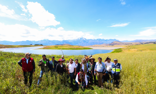 Autoridades y el equipo técnico del proyecto al lado de las lagunas con cielo azul intenso.