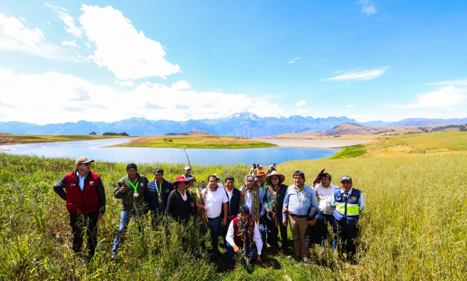 Autoridades y el equipo técnico del proyecto al lado de las lagunas con cielo azul intenso. 