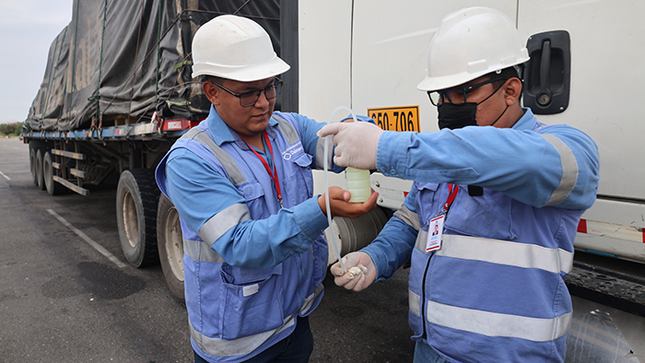 Fotografía de dos supervisores de Osinergmin extrayendo una muestra de combustible del tanque de un vehículo de transporte internacional. 