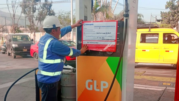 Supervisor de Osinergmin coloca un letrero de clausura sobre un surtidor de combustible