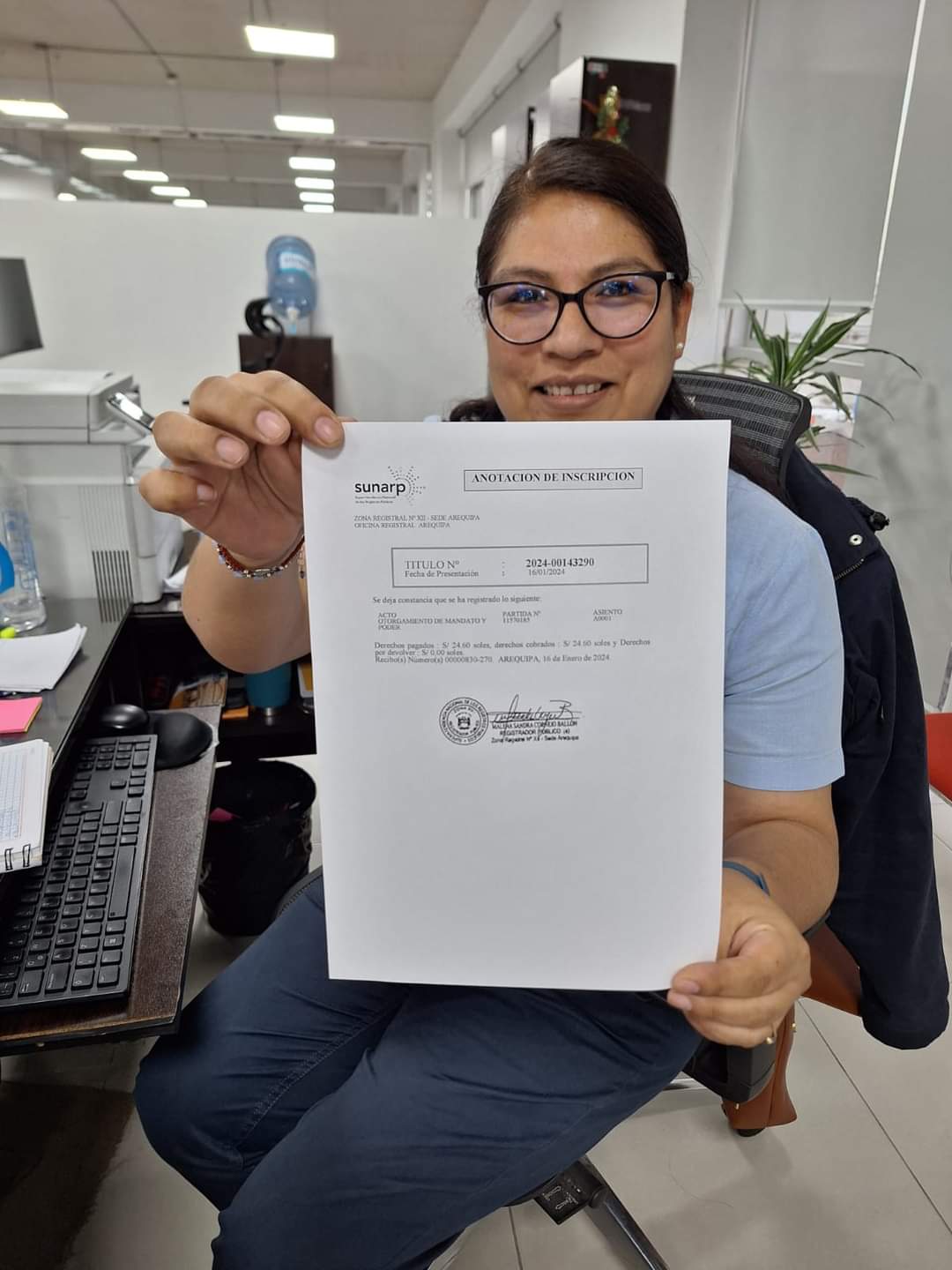 Foto de Mujer trabajadora de Sunarp mostrando poder consular impreso