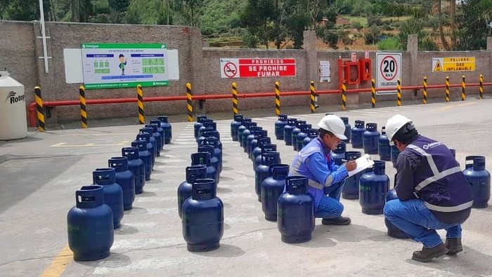 Dos fiscalizadores de Osinergmin en cuclillas, supervisando la calidad de balones de gas GLP