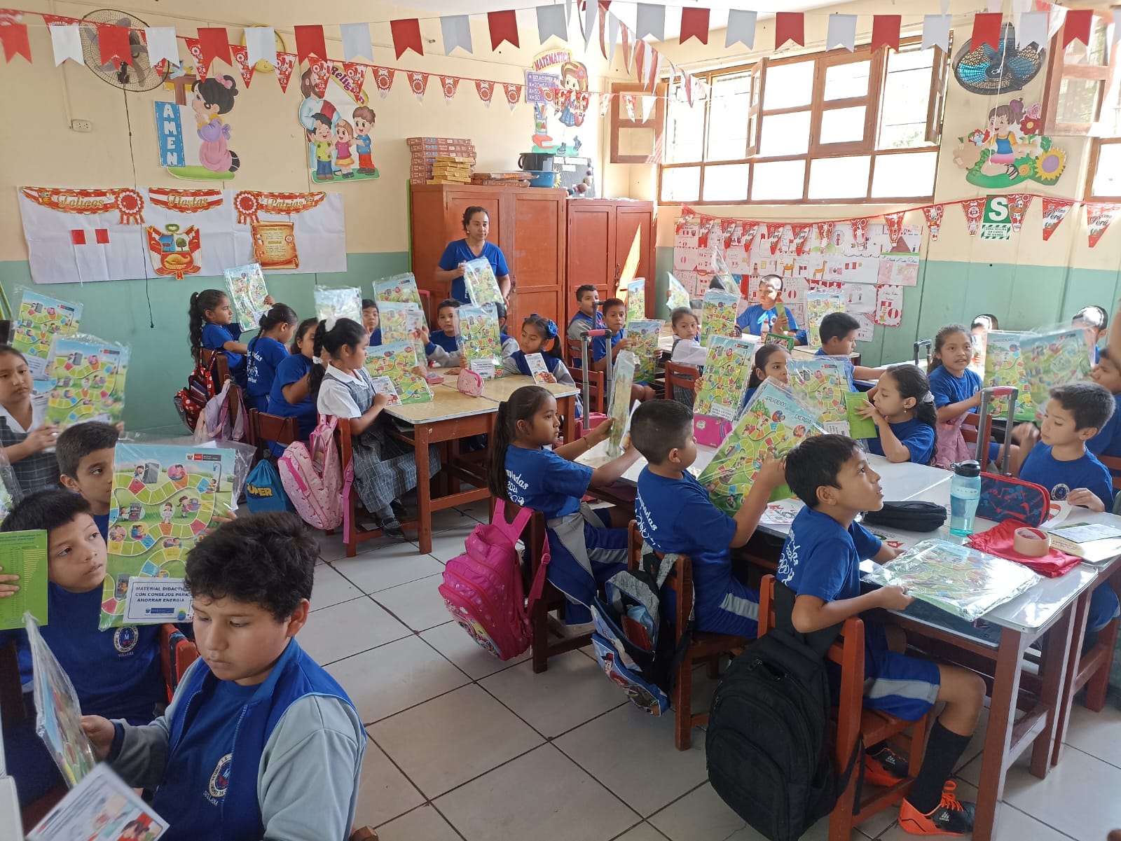 Salón de clases y niños recibiendo el material didáctico