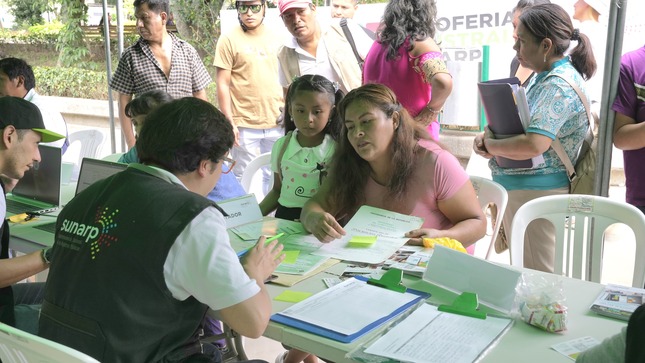 Foto de Colaborador de Sunarp brinda información a señora en la Expoferia Cusco