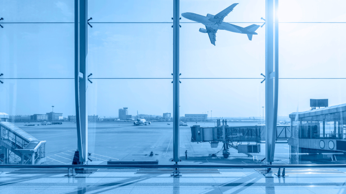Foto de un avión despegando. Vista desde el interior de aeropuerto a través de la ventana