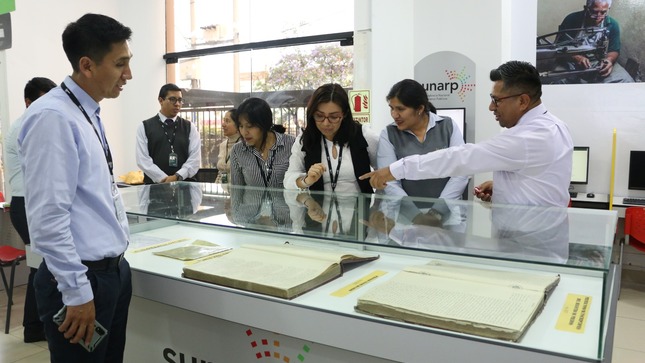 Foto de Personas mirando urna donde se encuentra registro de archivo histórico