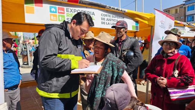 Foto de Trabajador de la Sunarp brinda información a señora, mientras tres personas más esperan su turno en Expoferia