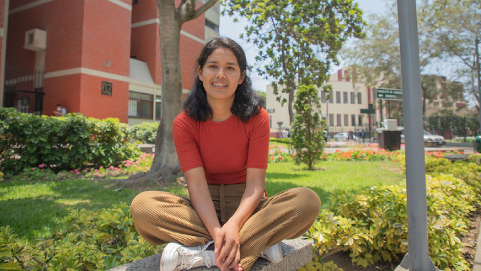Estudiante de la UNI y ganadora de Beca Permanencia sentada en el pasto de su universidad