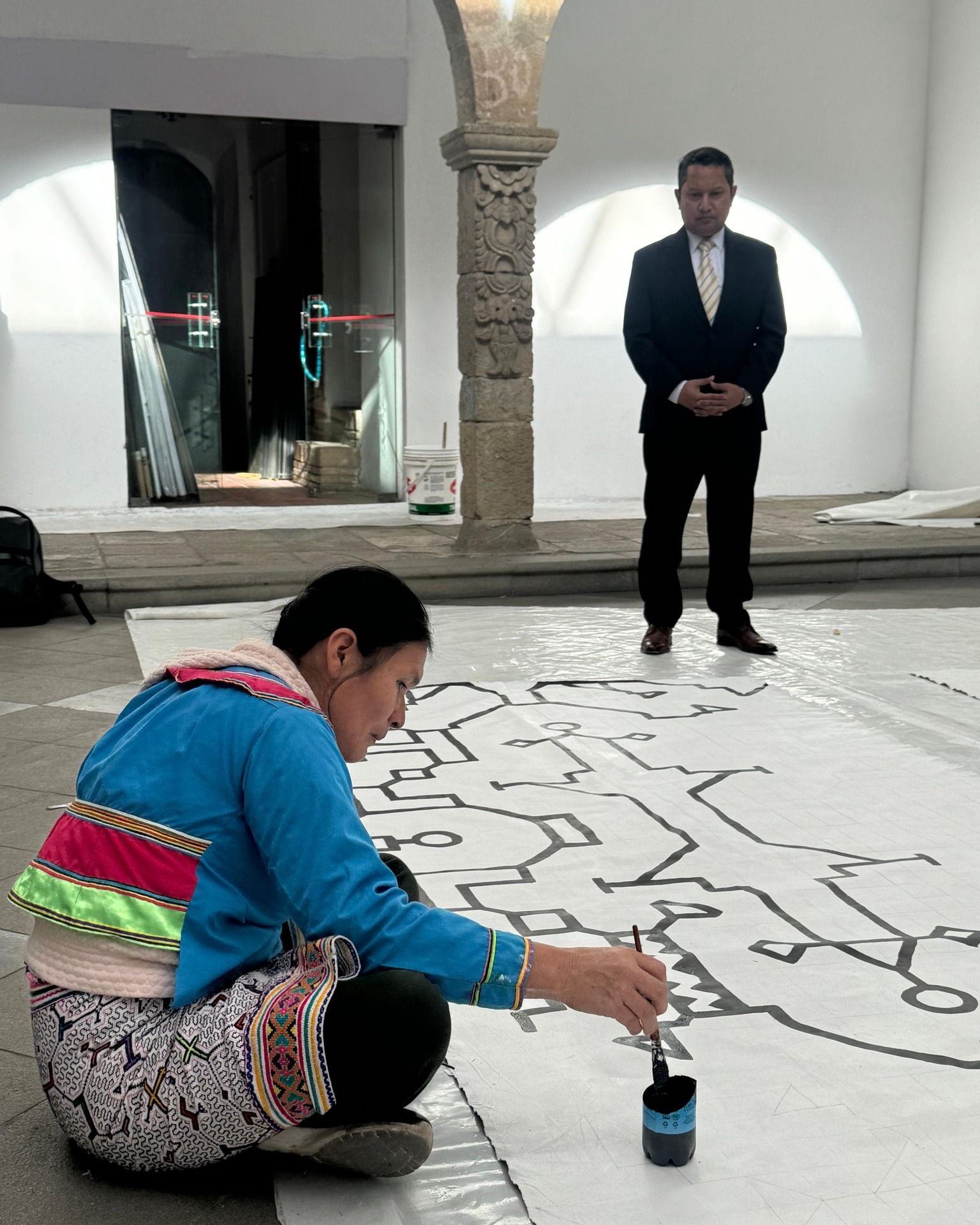 Artista shipibo-konibo Delia Pizarro pinta un telar ante la atenta mirada del Encargado de Negocios