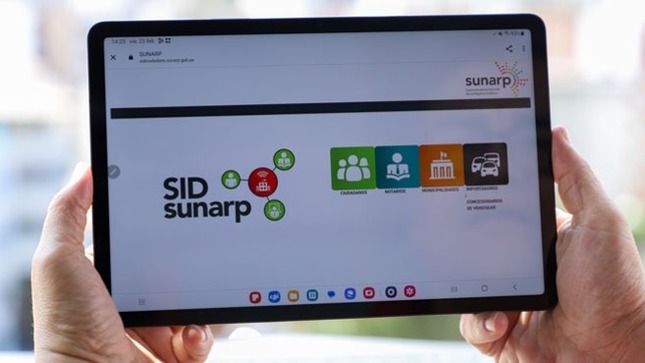Foto de las manos de una persona sosteniendo un tablet que tiene abierta la aplicación del  Sid Sunarp