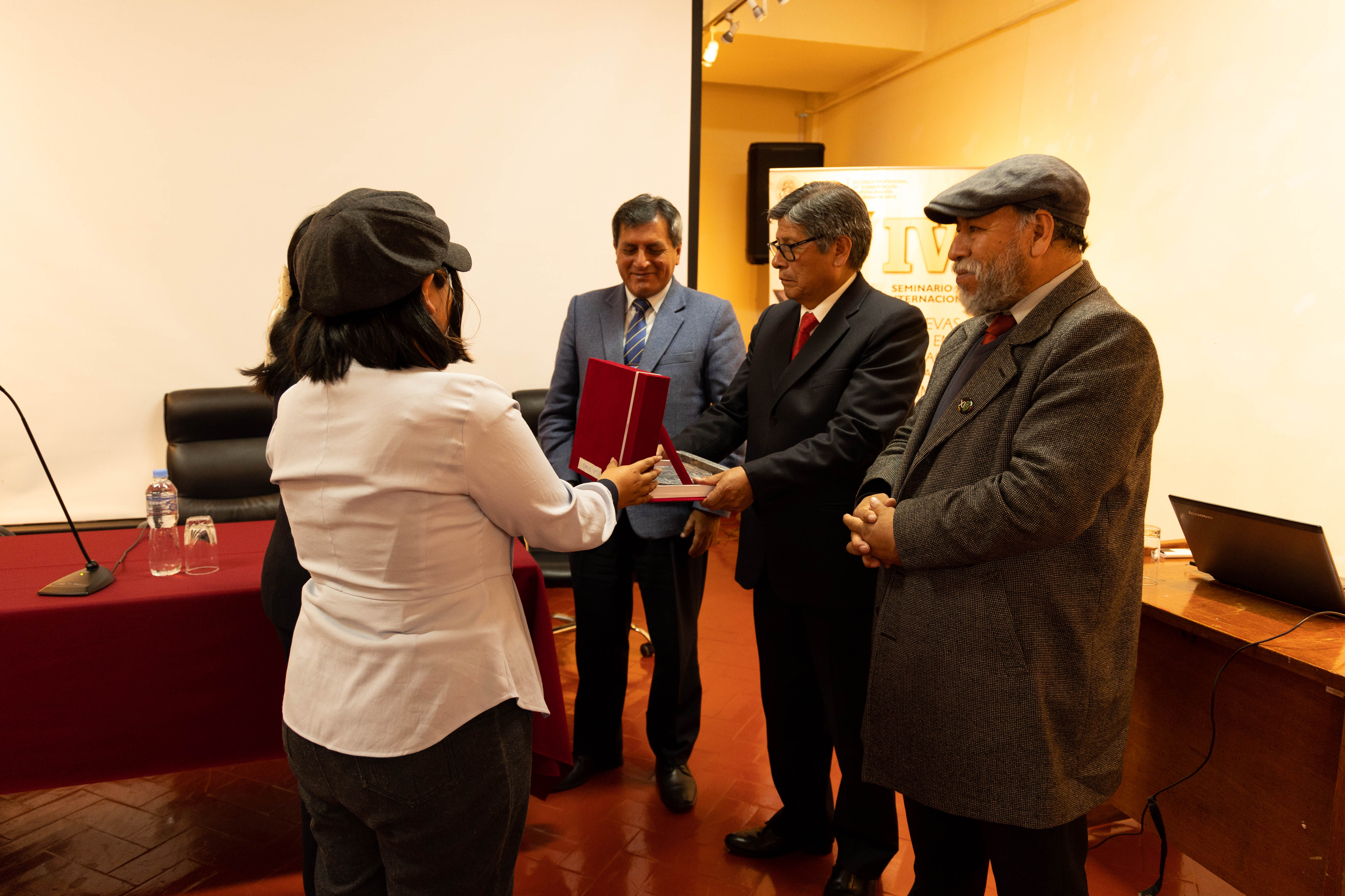 Docente y estudiante hacen entrega del premio a la Comisión Organizadora