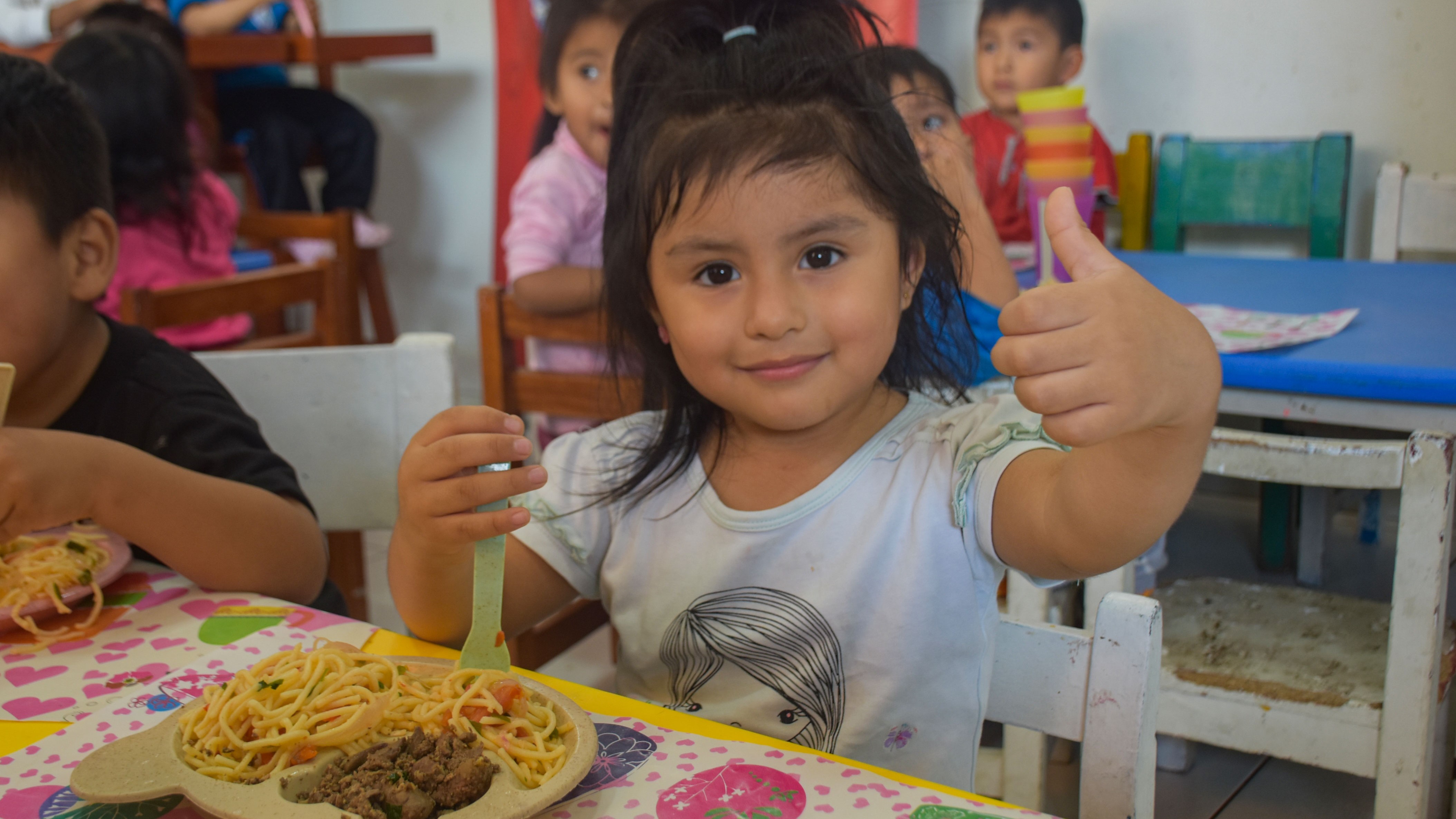 Una pequeña usuaria de educuna toma su desayuno.