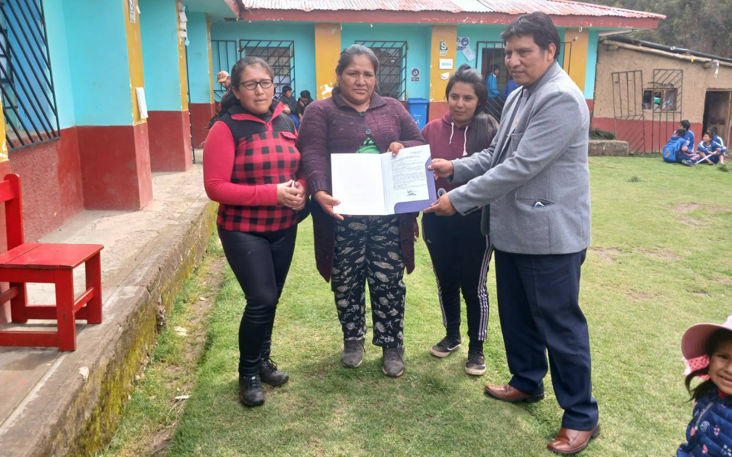 Fotografía del director de la UGEL Cotabambas sosteniendo el titulo predial junto a decentes.