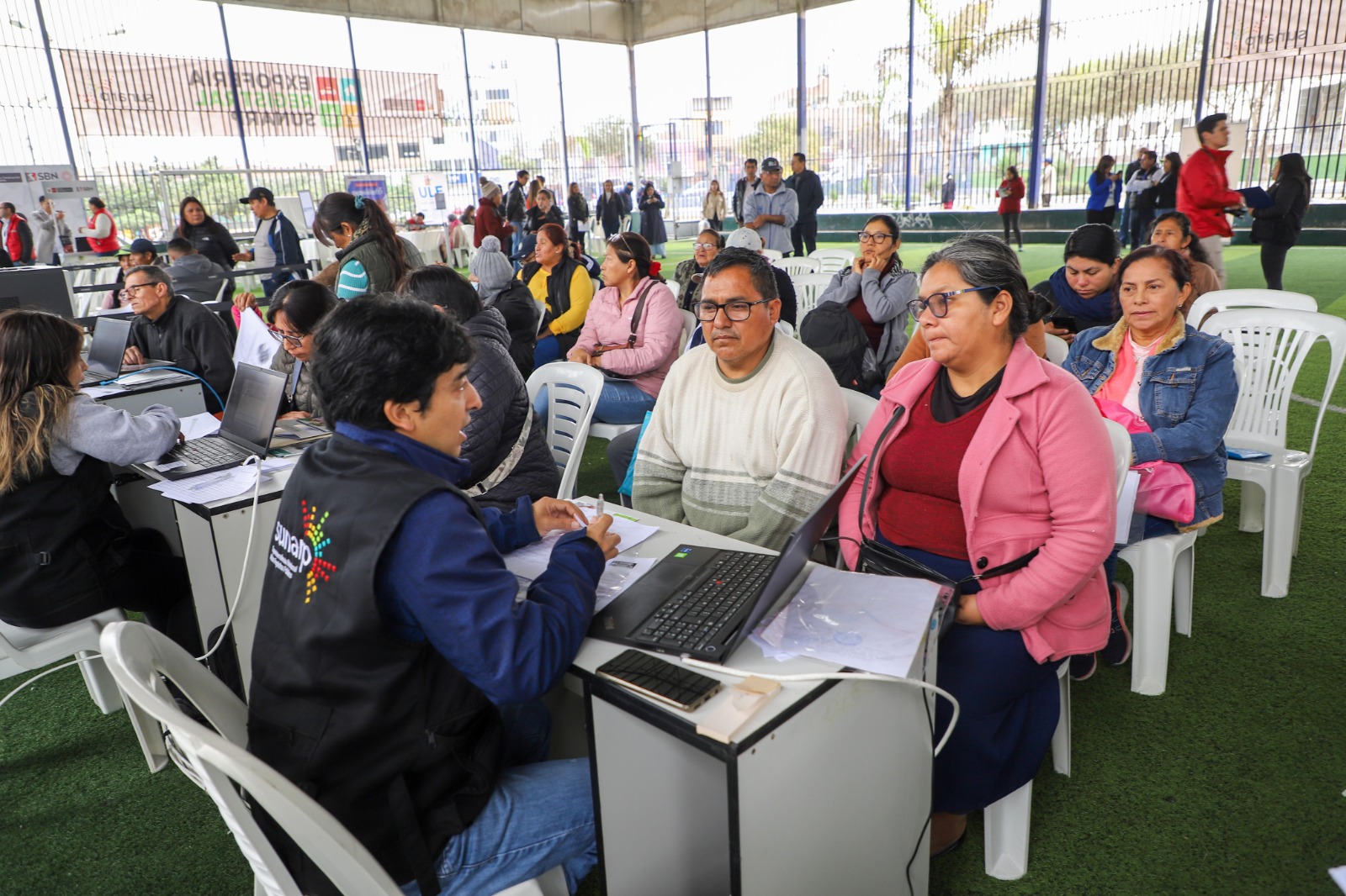 Foto de Servidores de Sunarp brindan información a varias personas en evento organizado por la entidad
