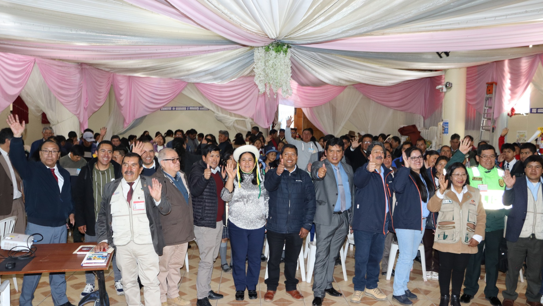 Autoridades de los seis distritos de Cotabambas, representantes de Minera Las Bambas, la Policía Nacional del Perú, dirigentes del SUTEP, estudiantes, docentes y padres de familia, todos en conjunto saludando a la cámara.