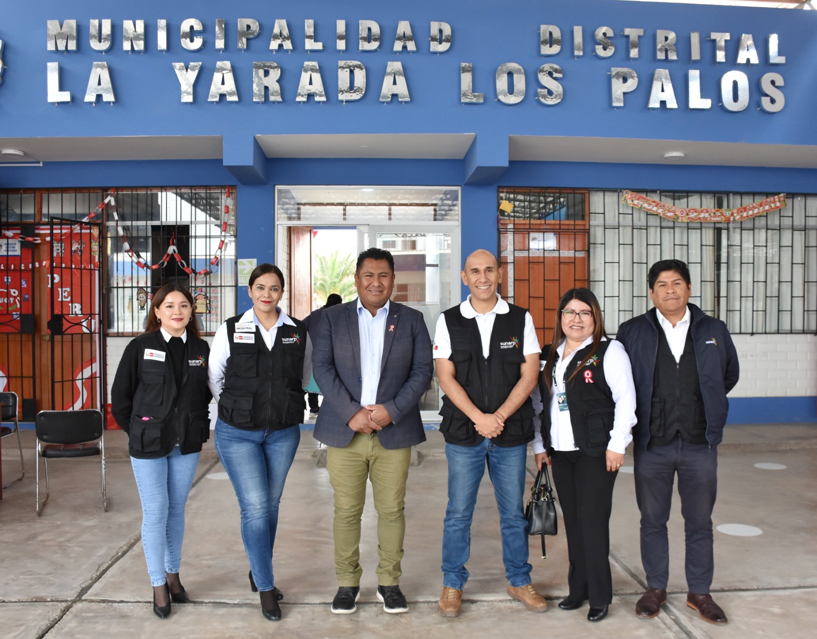 Foto de Funcionarios de la Municipalidad Distrital de La Yarada y funcionarios de Sunarp posan para la foto delante del local municipal