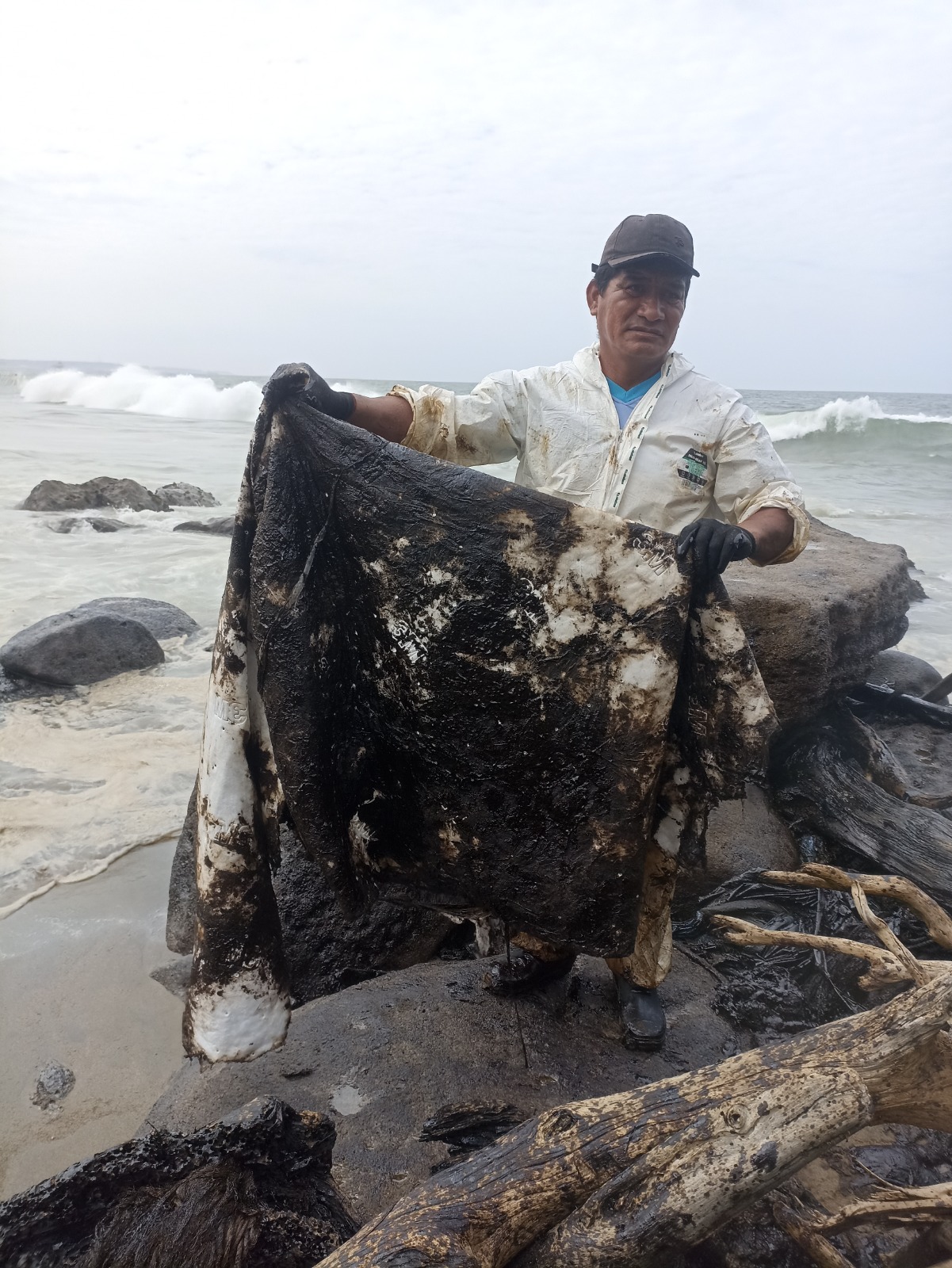 Poblador retirando el hidrocarburo de las rocas de la playa