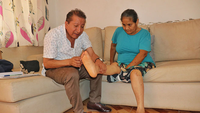 Médico certificador revisando la extremidades inferiores de un adulto mayor
