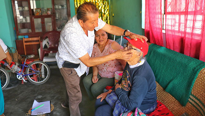 Médico certificador revisando los ojos de un adulto mayor