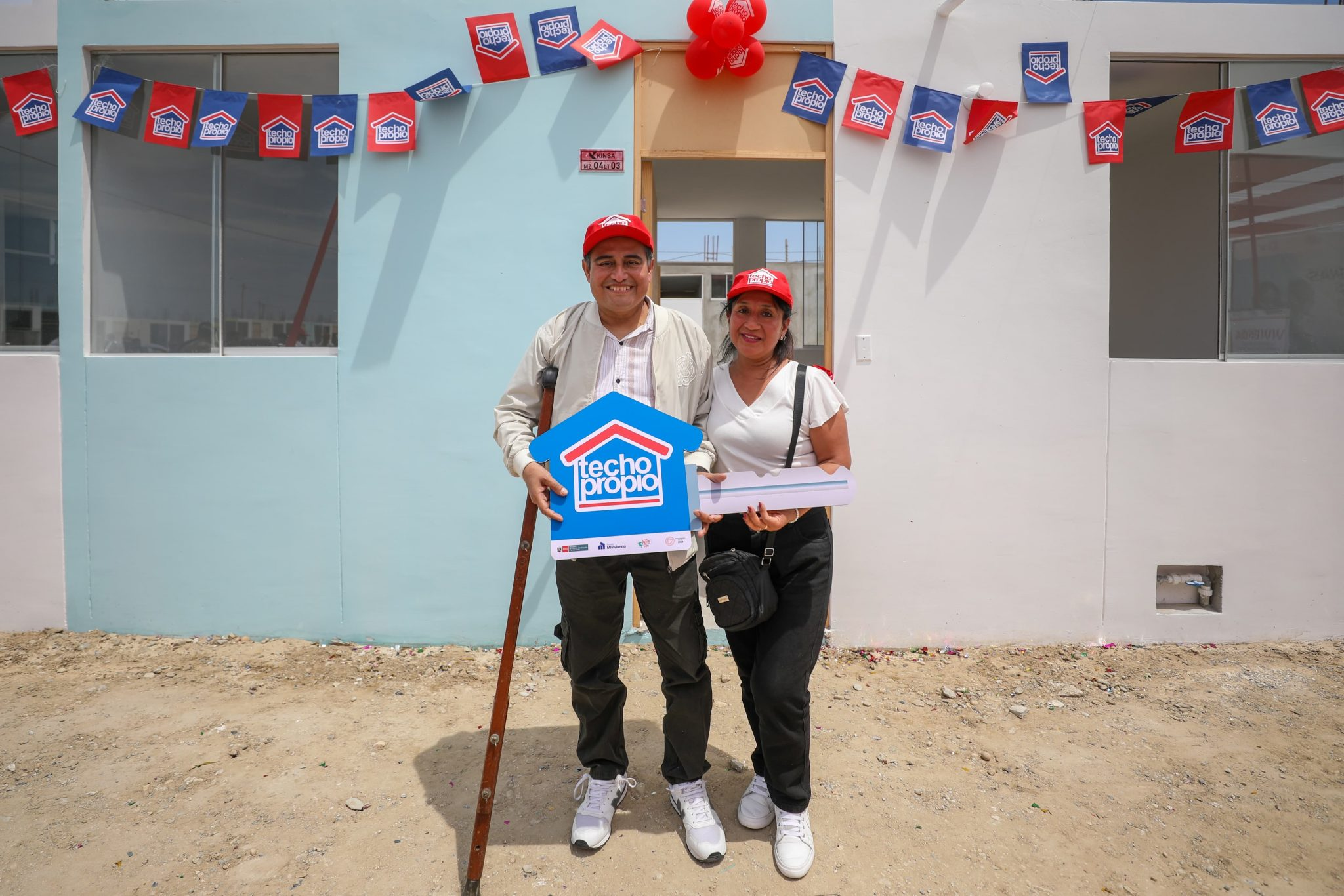 Personas con discapacidad severa mostrando el cartel de Techo Propio
