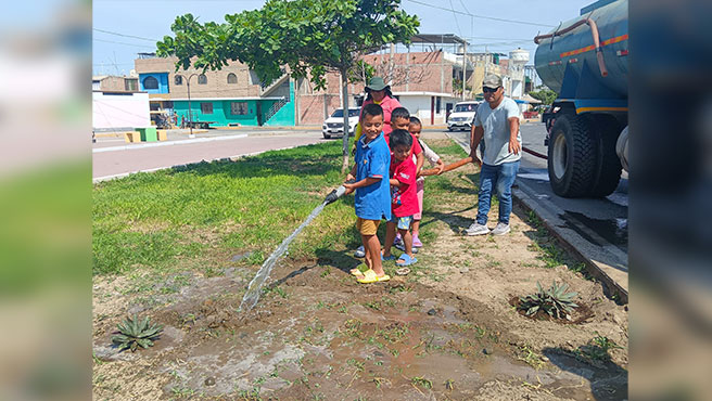 Equipo municipal enseñando a los niños a regar las áreas verdes 