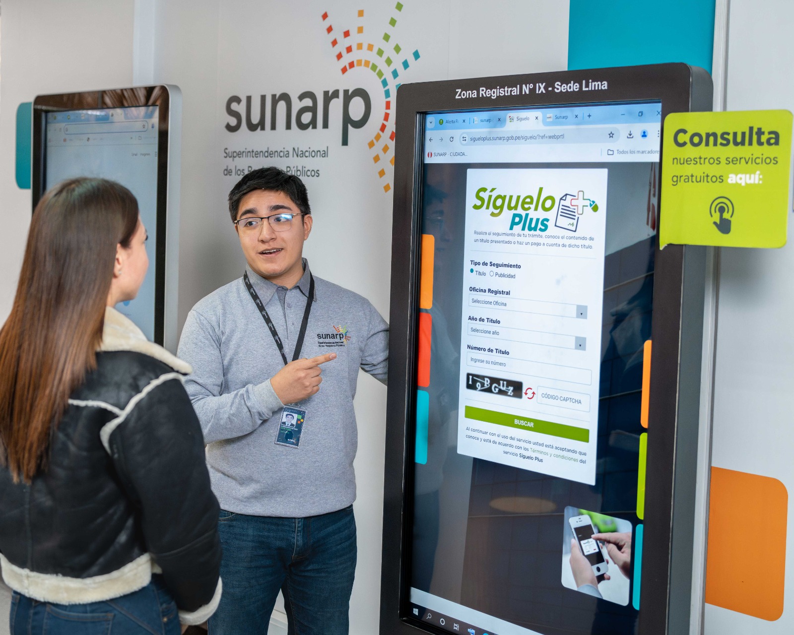 Foto de Colaborador de Sunarp muestra a una mujer, pantalla con información sobre servicios de la Sunarp