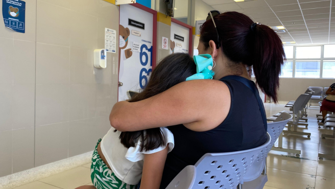 Madre y su niña en brazos en sala de espera de un hospital