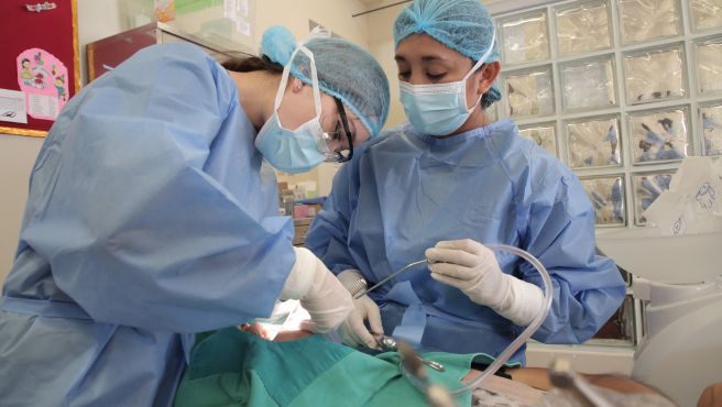 Pasante extranjera realizando procedimiento dental en el Heves