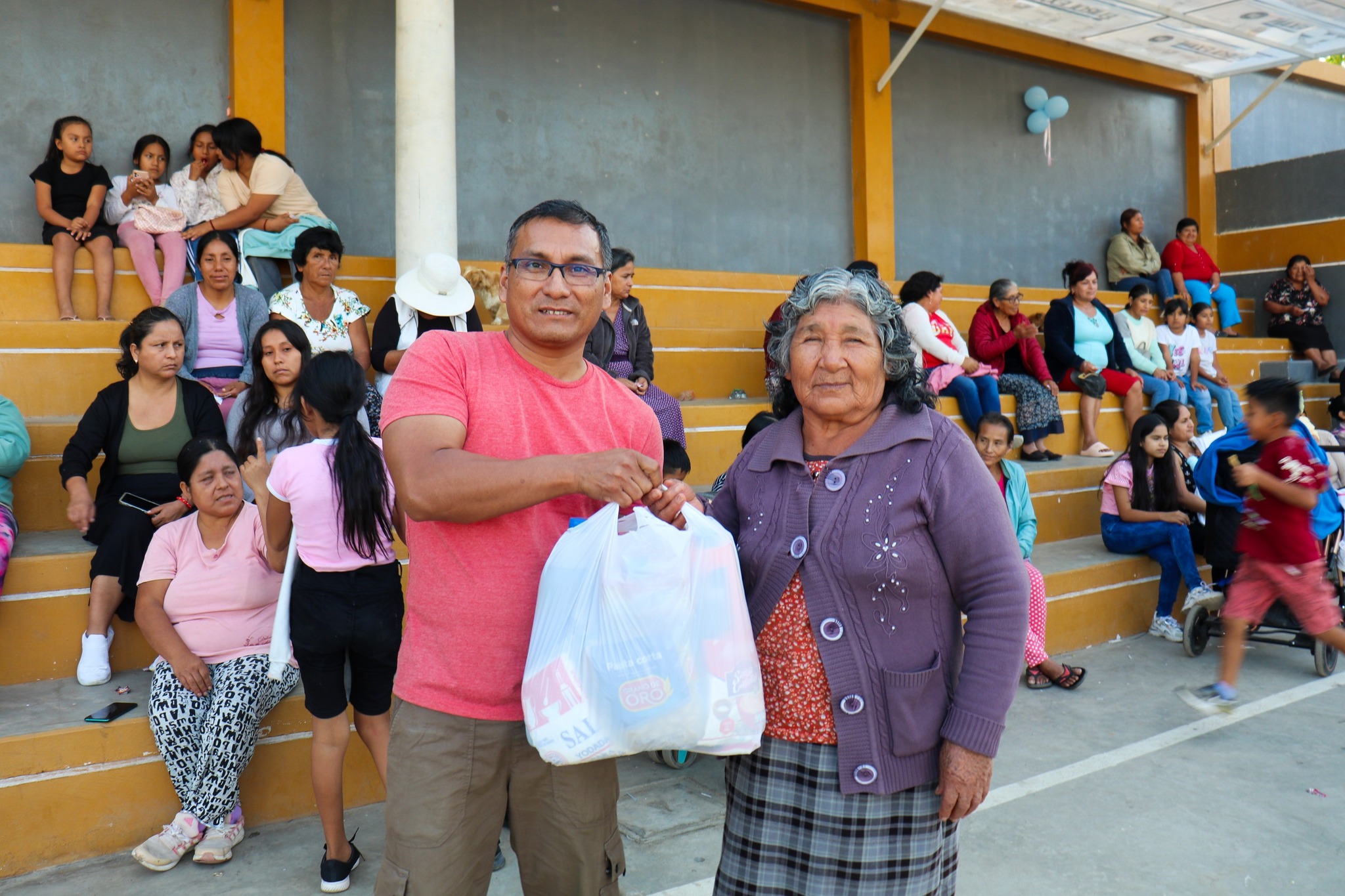madre recibe una bolsa de viveres