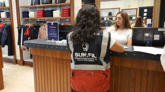 Persona en mostrador rodeada de ropa