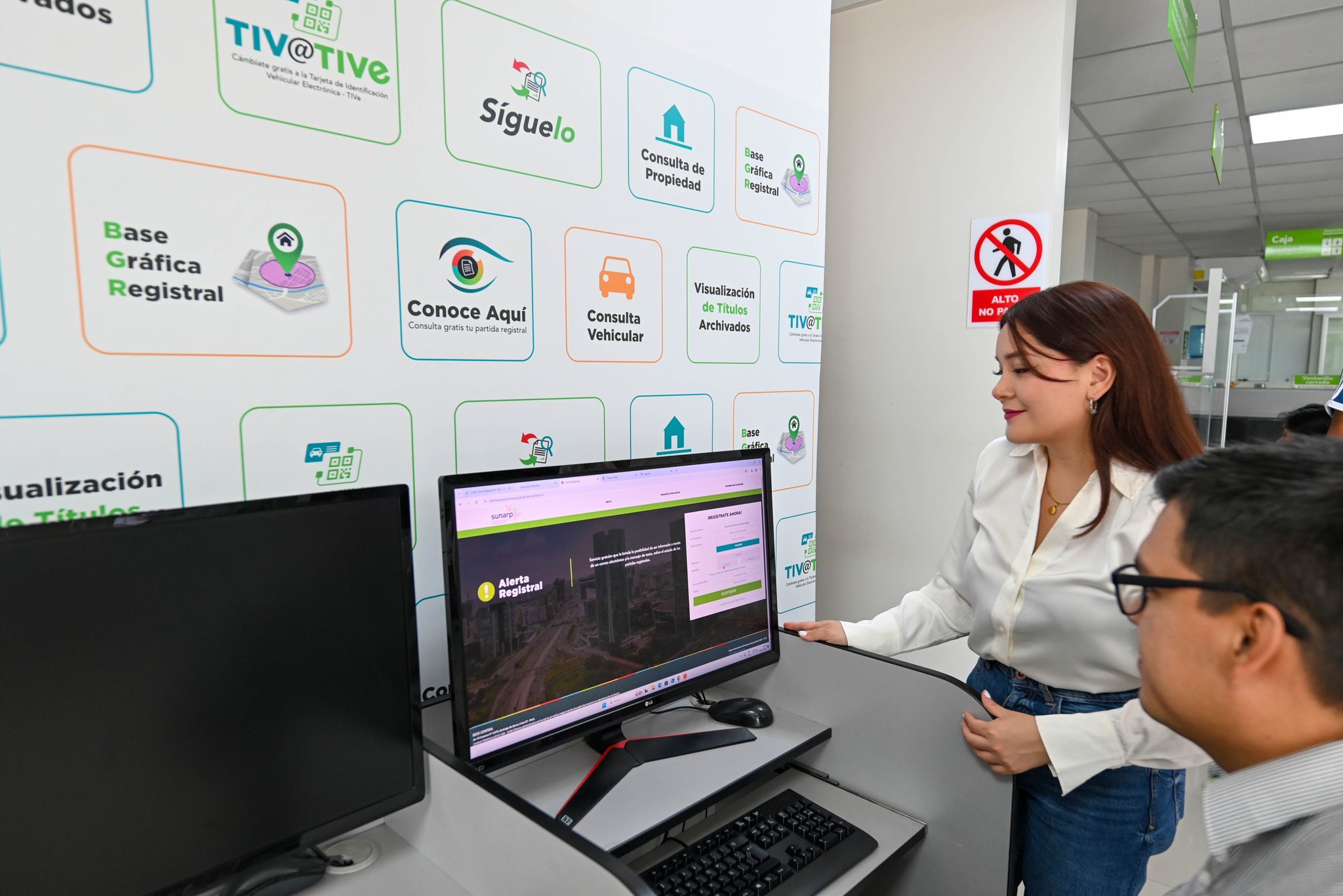 Foto de Dos personas observan pantalla de PC donde se visualiza el acceso a una plataforma registral de Sunarp
