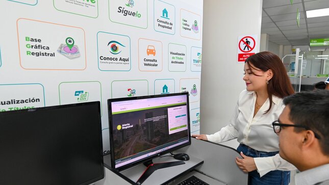 Foto de Dos personas observan pantalla de PC donde se visualiza el acceso a una plataforma registral de Sunarp