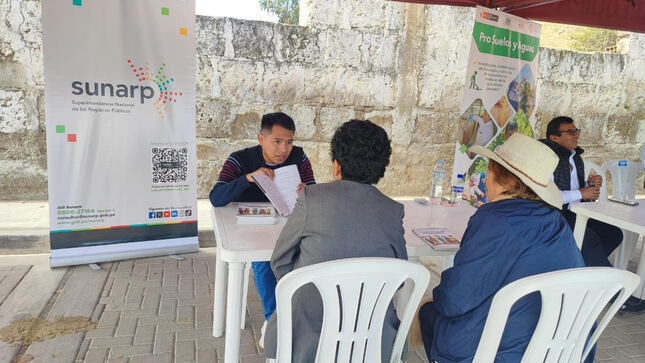 Foto de Un trabajador de Sunarp brinda información a una pareja de adultos mayores en módulo de atención